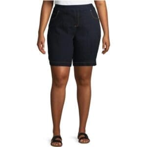 A person wearing Denim Mid Rise Tum Cont knee-length shorts, a white top, and black sandals stands against a plain white background.