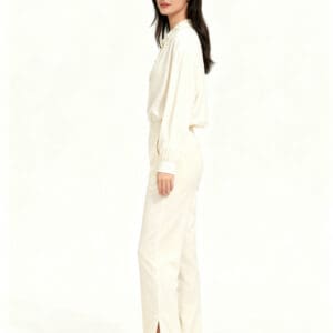 A woman wearing a cream-colored long-sleeved blouse and matching Thick Crinkly Cotton Pants with side-slit hems.