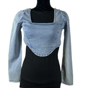 A long-sleeve denim crop top with a square neckline is layered over a black fitted shirt, displayed on a black mannequin torso against a white background.