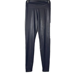 Black faux leather leggings hanging on a hanger against a white background.