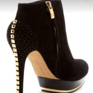 Black suede high-heeled ankle boot with a gold-studded heel, gold zipper, and platform sole.