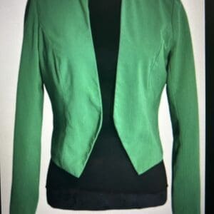 A fitted, open-front green blazer with long sleeves, shown over a black top on a display mannequin.