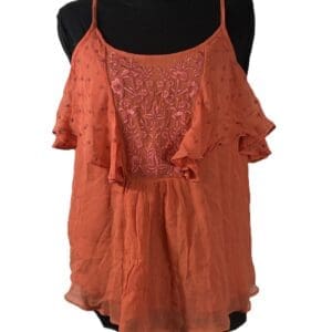 Sleeveless, coral-colored women's top with thin straps, ruffled sleeves, and floral embroidery on the chest, displayed on a black mannequin.