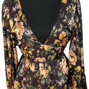 A long-sleeve floral blouse with a deep V-back, featuring pink and yellow flowers on a dark background, displayed on a mannequin.