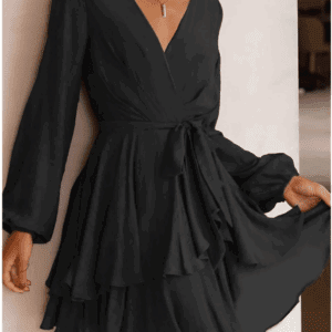 A woman stands indoors smiling, wearing the Black Short Ruffle Jogger Sleeves Dress featuring a V-neck, ruffled skirt, long sleeves, and waist tie.