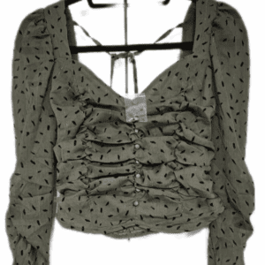 Green Top W/Black Spots Tie Neck, featuring long sleeves, crop fit, black dotted pattern, and a square neckline with front ruching and buttons, shown on a hanger.