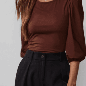 Woman wearing a Tied Brown Top and high-waisted black trousers, standing against a plain background.