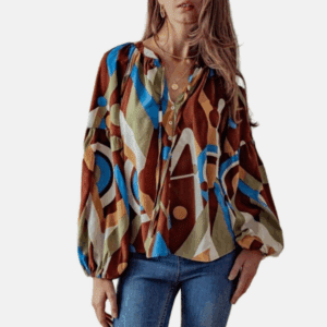 Woman wearing a Brown & Blue Colorful Button Down String Tie Neck blouse with geometric patterns, balloon sleeves, and blue jeans, accessorized with layered gold necklaces.