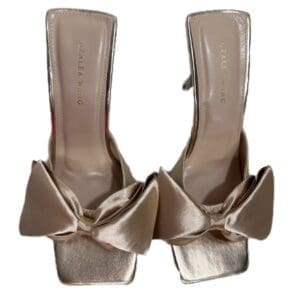 A pair of open-toe Rae Beige Bow flip flops with large satin bows on the front, featuring the brand name "AZALEA WANG" on the insoles.