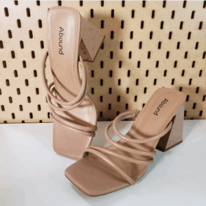 A pair of nude, open-toe, block-heeled sandals with three thin straps and square toes, displayed against a pegboard background.