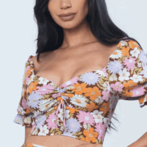 A woman wears a colorful, floral-patterned crop top with puffed short sleeves and a ruched front detail.
