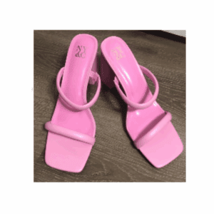 A pair of pink, open-toe heeled sandals with square toes and two straps, placed on a wooden floor.