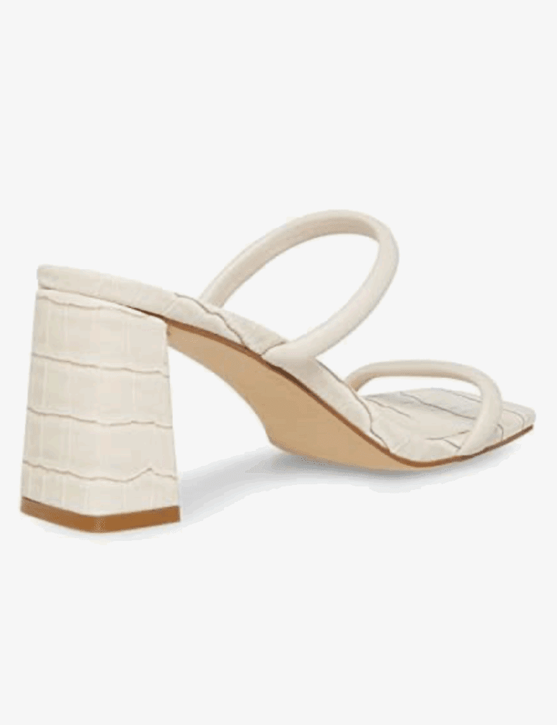 A heeled sandal with a square toe, two thin straps, and a textured block heel in an off-white color.