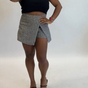 A person wearing a black sleeveless top, a Small Checkered Skort, and black heeled sandals, posing against a plain white background.