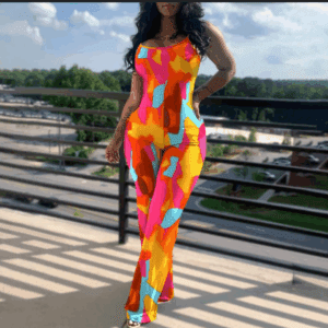 A woman wearing the Colorful Jumpsuit stands on a balcony overlooking a parking lot, trees, and a partly cloudy sky.