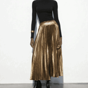 A person models the Gold Pleated Skirt with a black long-sleeve top, black ankle boots, and a gold bracelet while standing against a plain white background.