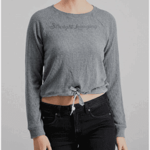 A woman wears the Drawstring Bottom Long Sleeve Top—a ribbed, gray, long-sleeve crop top with a front tie—paired with black jeans, standing against a plain background.