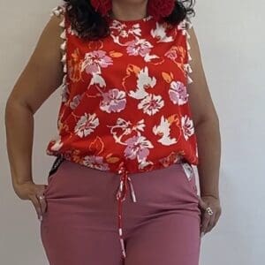 Person wearing a Sleeveless w/ White Tassels top and pink pants, standing against a plain light-colored background.