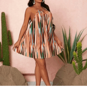 A woman wearing a Halter Dress stands indoors between potted cacti, posing against a light pink wall.