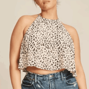 A person wearing the Spaghetti Strap Cheetah Top—a sleeveless, loose-fitting cropped top with a black and beige animal print—paired with high-waisted blue jeans.