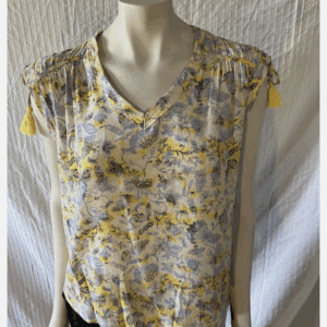 A mannequin showcases the Flower Tassle Short Sleeve Top, a yellow and blue floral V-neck blouse with tassel-embellished shoulders, paired with black pants.