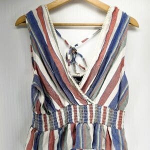 The Stiped Low V neck Tie Back Crop Top features a sleeveless, striped design with a tie-back and elastic waist, shown on a wooden hanger against a white background.