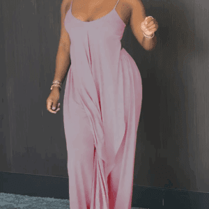 A woman stands indoors against a dark wall, wearing a pink 2-piece wide leg pants set.