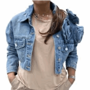 A person wearing a light brown t-shirt, cropped denim jacket with button details, and a wristwatch, with hands in pockets.