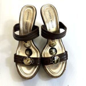 A pair of Antonio Melani Strapless 3 Jewel Wedge women's brown heeled sandals with decorative marbled stones on the straps, displayed on a white surface.