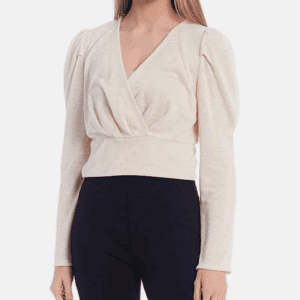 A woman wearing the Off the Shoulder Be Bold Top, a cream-colored long-sleeve wrap top with puffed shoulders, paired with black pants.