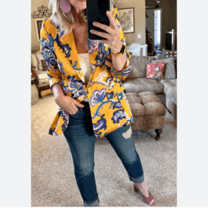 Person taking a mirror selfie in a living room wearing the Flowered Blazer, a yellow top, distressed jeans, and mauve heels.