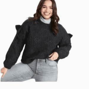 A woman wearing a black Ruffle Sleeve Sweater and light gray jeans stands against a plain white background, smiling with one hand on her hip.