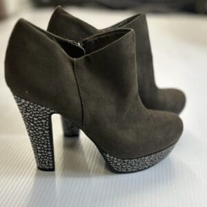 A pair of black suede high-heeled ankle boots with platform soles and heels decorated with small silver studs.