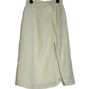 The Sage The Label Cream Side Slit Skirt is a knee-length, wrap design in cream, featuring a side slit and shown on a black hanger against a white background.