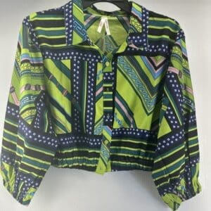 The True Destiny Green Themed Button Down Top is a long-sleeve shirt featuring multicolored geometric and striped patterns in green, blue, black, pink, and white, displayed on a hanger against a plain background.