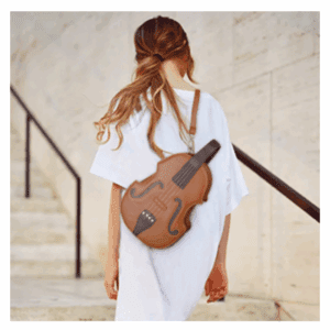 A woman in a white dress walks up stairs, carrying a brown crossbody Guitar Bag with Strap.