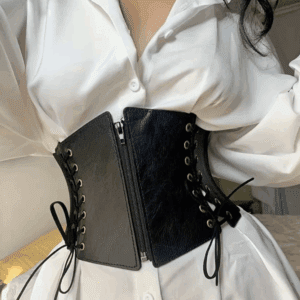 Person wearing a white button-up shirt and a black leather corset belt with laces and a front zipper.