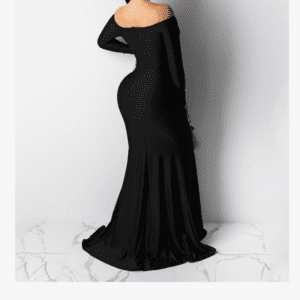 A person wearing Product, a fitted, off-the-shoulder long black gown, is seen from the back standing on a white floor with gray veining.
