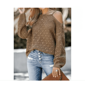 A woman wearing a brown, off-shoulder, knit sweater and light blue high-waisted jeans, holding a brown clutch bag outdoors.