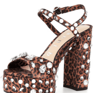 A high-heeled platform sandal with a leopard print design, decorated with pearls, rhinestones, and metallic studs, and featuring a crossed ankle strap.