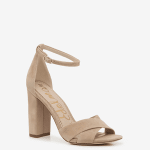 A beige suede high-heeled sandal with a block heel, ankle strap, and crisscross front straps on a plain white background.