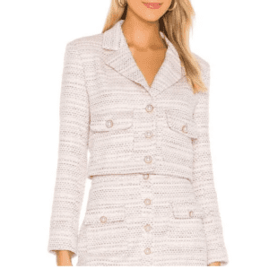 Woman wearing the Song of Style "Sophia" Crop Blazer in light pink tweed with gold buttons and front flap pockets, paired with a matching skirt.