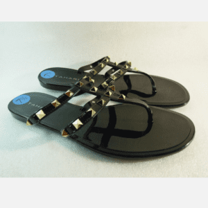 A pair of shiny black flat sandals with two straps decorated with gold studs and a blue size sticker labeled "7½" on each insole.