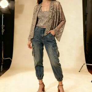 A woman poses in a studio wearing the TT Lace Layering Cardigan (size L/XL), paired with a patterned top, high-waisted cargo jeans, and studded heeled sandals.