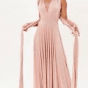 A woman wearing a sleeveless, floor-length blush pink dress with long, wide straps draped from the shoulders.