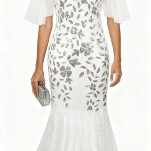 A woman wearing a white, floor-length gown with sheer short sleeves and silver leaf embellishments, holding a silver clutch and wearing drop earrings.