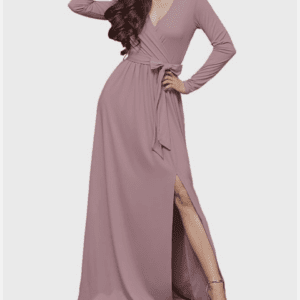 Woman wearing a long-sleeve, mauve wrap dress with a belt at the waist and a high slit on one side, posing with one hand on her hip and the other touching her head.