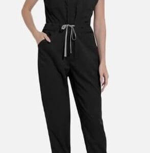 A woman wearing a black short-sleeve jumpsuit with a drawstring waist and white sneakers, standing against a plain background.