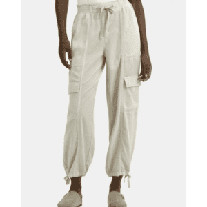 Person wearing light beige cargo pants with drawstring waist and ankles, paired with a white top and beige slip-on shoes, standing against a plain background.
