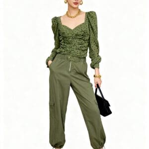 A woman in a green polka dot top and green cargo pants, holding a black handbag.